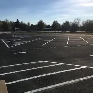 Directional arrow and white linework on a dark parking area