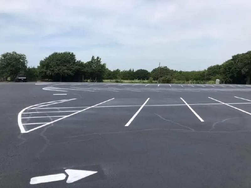 Parking-lot markings and a directional arrow with trees on the horizon